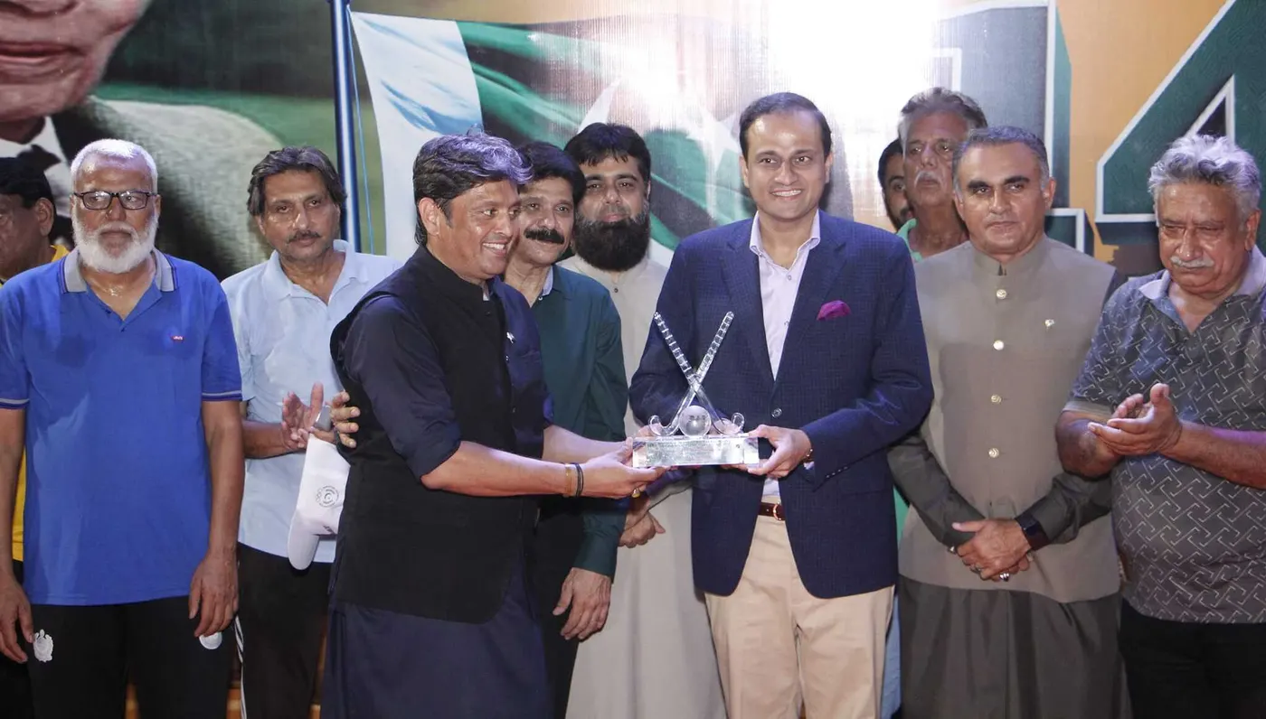 Officials and guests on stage as a glass crossed-sticks trophy is presented at a Karachi Hockey Association event
