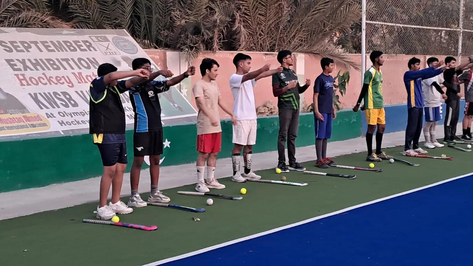 Young players lined up with their sticks and training balls at the edge of the turf