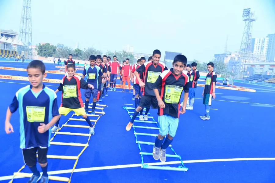 Boys in KHA Winter Hockey Coaching Camp 2024 bibs running an agility-ladder drill on the blue turf